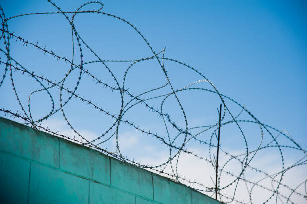 istock Barbed fence around prison walls 972032520