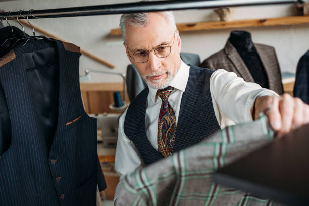 istock confident mature tailor examining clothes at sewing workshop 972032974