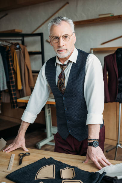 istock handsome mature tailor standing at workplace in sewing workshop 972035154