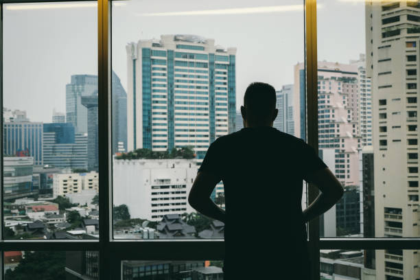 istock Man looking at modern Bangkok district from the window 972048544