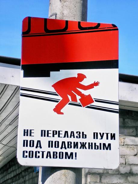 June 24th, 2006, Trans Siberian railway Line, Siberia, Russia.  A sign in cyrilic seen from the station's platform, warns passengers not to go under the train to get to the opposite platform as it's too dangerous.