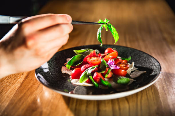 istock Chef hand prepares a salad with  vegetables and decorates this meal with herbs 972057622