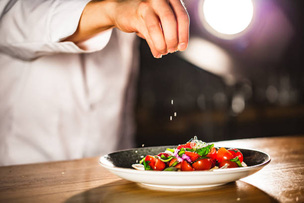 istock Closeup mid section of a chef putting salt in the kitchen 972057718
