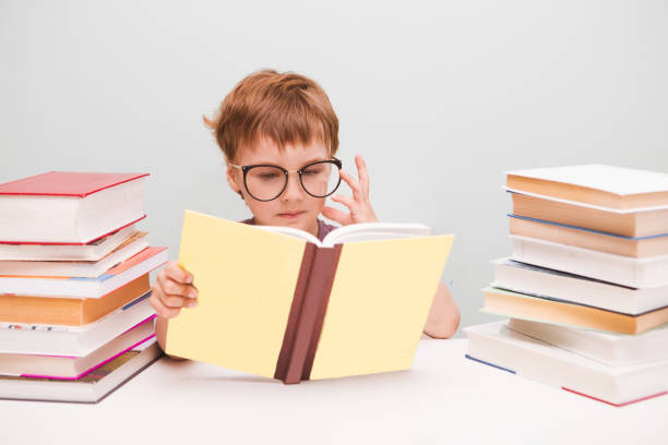 istock preschooler little boy in glasses reading a book. 972064292