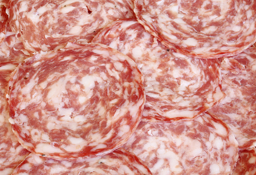 background of slices of Italian sopressa for sale in a butcher shop