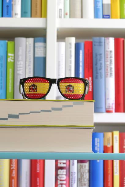 bandeira espanhola como óculos de sol em frente a uma estante de livros - paperback book stack book spine - fotografias e filmes do acervo