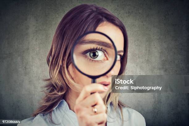 Donna Curiosa Che Guarda Attraverso Una Lente Dingrandimento - Fotografie stock e altre immagini di Lente d'ingrandimento