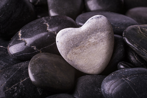 background with black stones and over a white stone heart