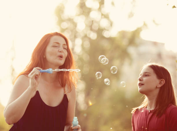 istock Mother and Daughter at the Park Blowing Soap Bubbles 972105490
