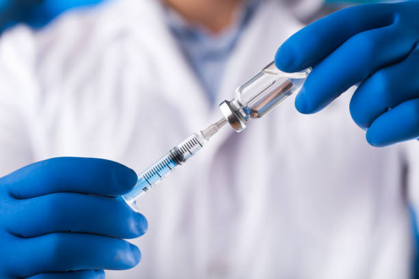 istock Medical hands holds syringe and vaccine 972105728