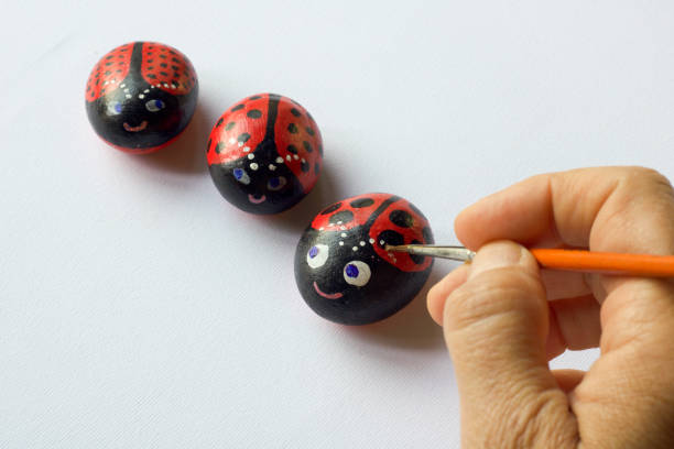 istock hand with brush painting three  stones as ladybugs 972126036