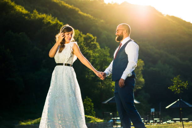 istock Bride and groom holding hands at sunset 972132010