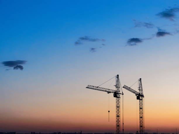 istock Pair of construction cranes against the sky at sunset 972137706
