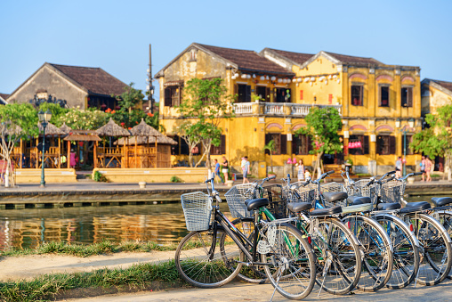 Scenic view of bicycles parked beside the Thu Bon River in Hoi An Ancient Town (Hoian), Vietnam. Traditional yellow buildings are visible in background. Hoi An is a popular tourist destination of Asia