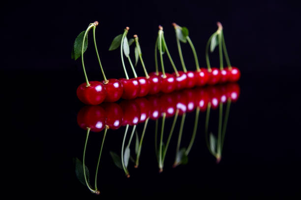 istock Sour cherry in a line reflection on a black glass surface 972151986