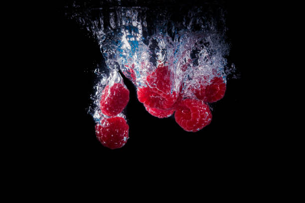 Raspberries falling into a water black
