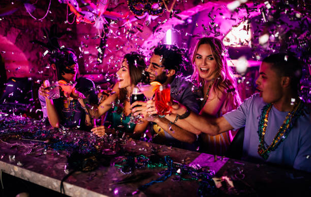 Friends celebrating Mardi Gras with drinks at night club Multi-ethnic friends partying with confetti and drinks at Mardi Gras party at New Orleans bar new orleans mardi gras stock pictures, royalty-free photos & images