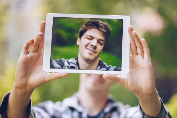 istock attractive and handsome young man taking a selfie with a tablet, making a silly spontaneous face. 972179142