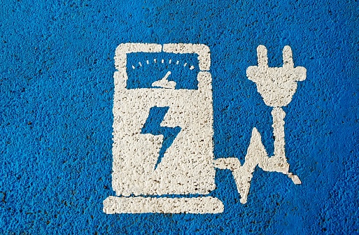 Electric vehicle charging public station sign on blue painted asphalt .