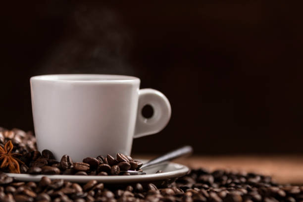 istock Cup of hot coffee with coffee beans on wooden table 972185080