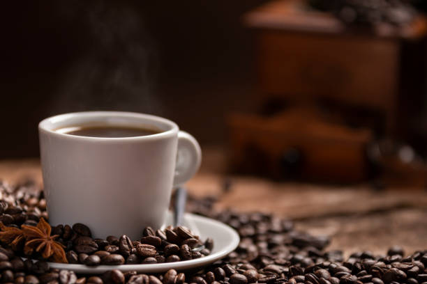 istock Cup of hot coffee with coffee beans on wooden table 972185082