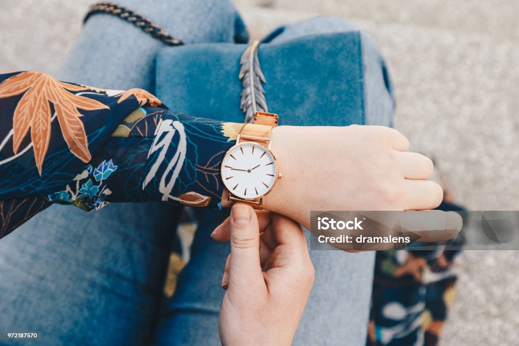 gros plan, mode jeune blogueur portant une jacker floral et une montre-bracelet analogique blanc et doré. regarder l’heure, tenant un sac à main en cuir suédé belle. - Photo de Montre libre de droits