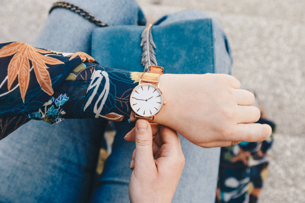 gros plan, mode jeune blogueur portant une jacker floral et une montre-bracelet analogique blanc et doré. regarder l’heure, tenant un sac à main en cuir suédé belle. - montre bracelet photos et images de collection