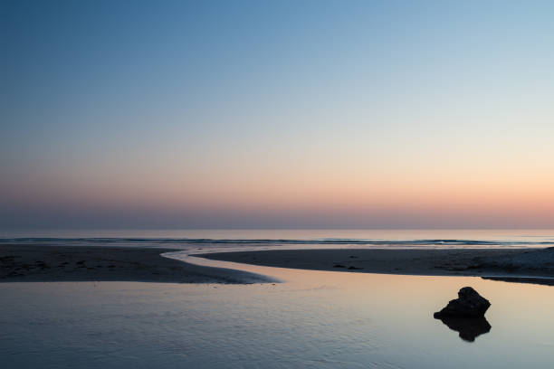 hermoso amanecer vibrante colorido sobre escena tranquila del paisaje de la playa de bajamar - bamburgh northumberland england beach cloud fotografías e imágenes de stock