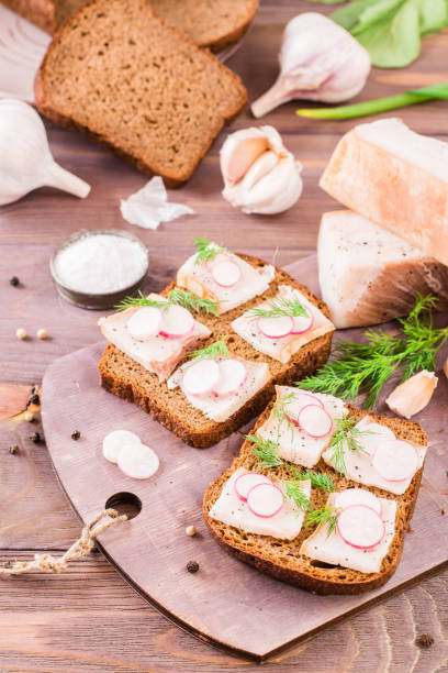 istock Sandwiches from rye bread, salted bacon, radish and dill on a cutting board 972203132
