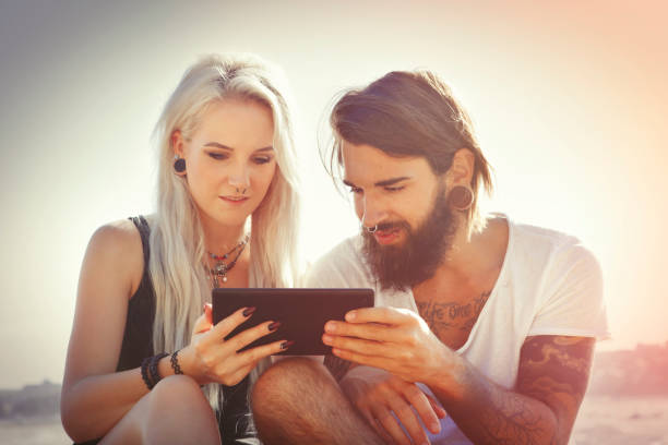 jeune couple sur la plage avec tablette - reading beach e reader men photos et images de collection