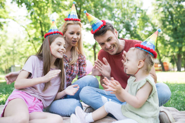 istock Parents with two children clapping hands and wearing party hats 972240230