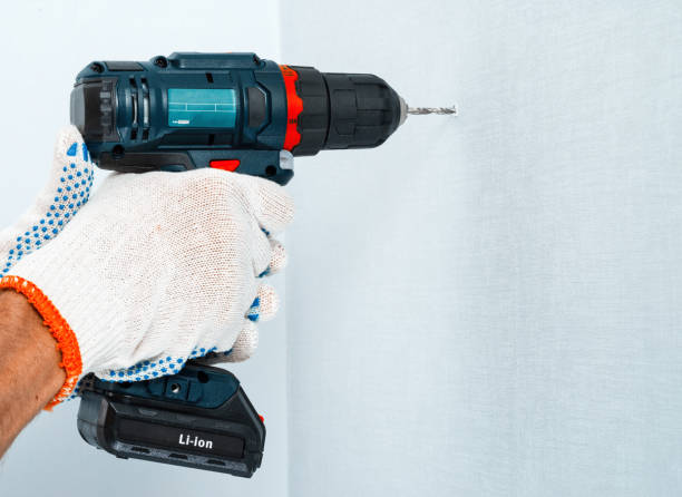 istock Drilling the wall with a cordless drill in protective gloves 972244990