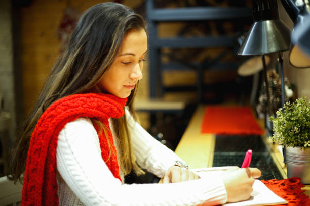 istock Young attractive woman writing diary in cafe 972250354