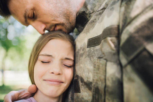 soldier leaning onto his sad daughter in emotion - homecoming imagens e fotografias de stock