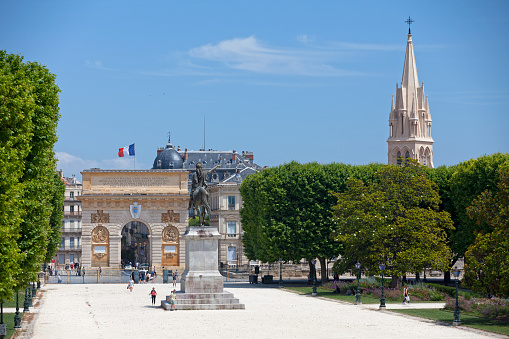 Montpellier, France - June 09 2018: Equestrian statue to the glory of Louis XIV and the Porte du Peyrou with the spire of the church Sainte-Anne.