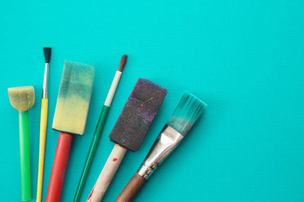 istock Children's Paint Brushes on a Teal Background 972268654