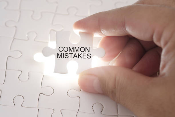 common mistakes word on jigsaw puzzle. businessman hands holding white puzzle business concept. - specific imagens e fotografias de stock