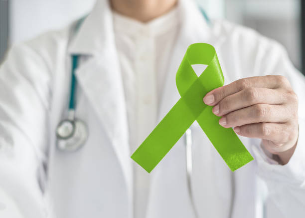 ruban vert dans la main du médecin pour cancer de lymphome et de santé mentale de sensibilisation, appui de chaux et d’aider les patients atteints de maladie - hodgkins disease photos et images de collection