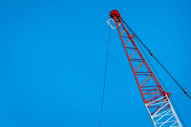 istock Red and white crane arm against blue sky 972379522
