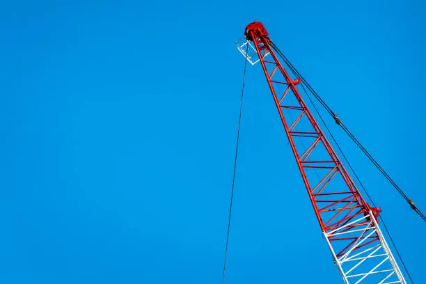 Red and white crane arm against blue sky
