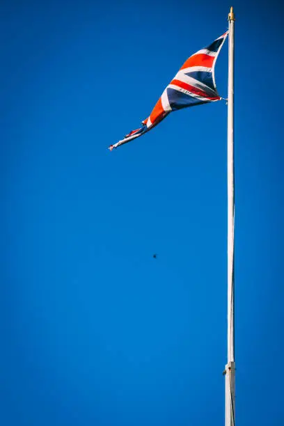 British Union Jack Flag on flag pole with blue sky background