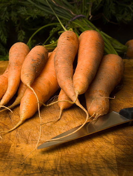 Organic Carrots on old wooden chopping board with knife stock photo