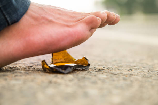 istock Bare feet walk over shards of broken bottle glass 972468286