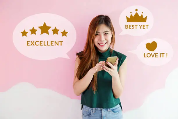 Photo of Customer Experience Concept. Happy Young Woman using Smart Phone to Review and Feedback Rating in Online Satisfaction Survey Application. Looking at camera with Smile