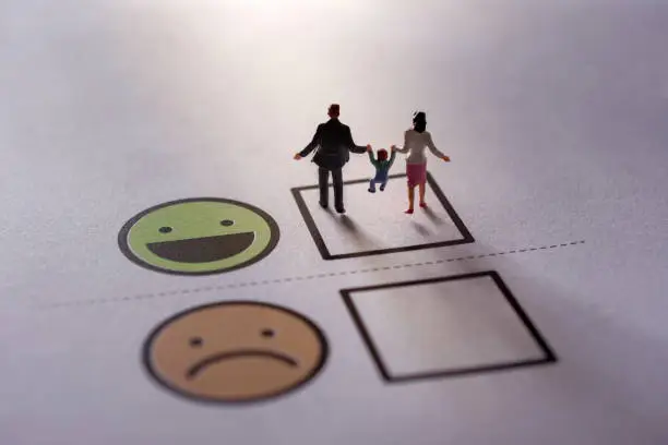 Photo of Happy Family Customer Concept. present by Miniature Figure of Father, Mother and Son in Happiness Moment. Walking on a Checked Box of Smiley Cartoon Face