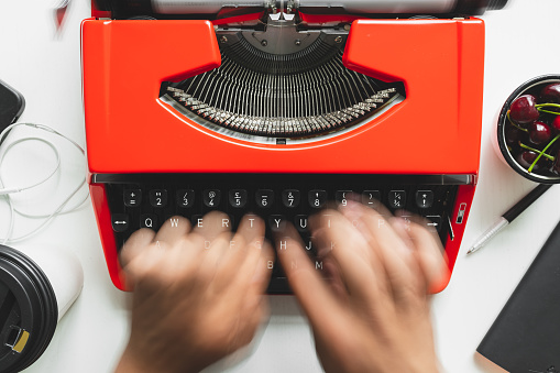 Top view of man hand working with bright red vintage typewriter