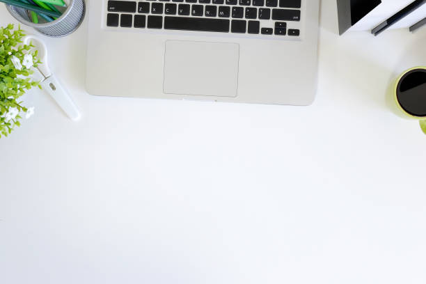 istock Office desk with workspace laptop computer, coffee cup and book on white table with top view. 972492414