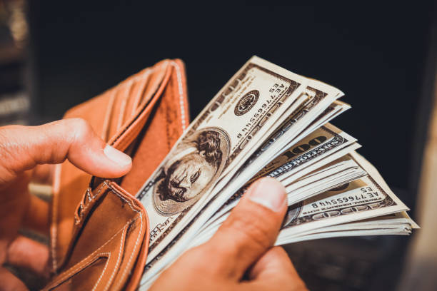 istock Hands holding us dollar bills and money pouch. 972498200
