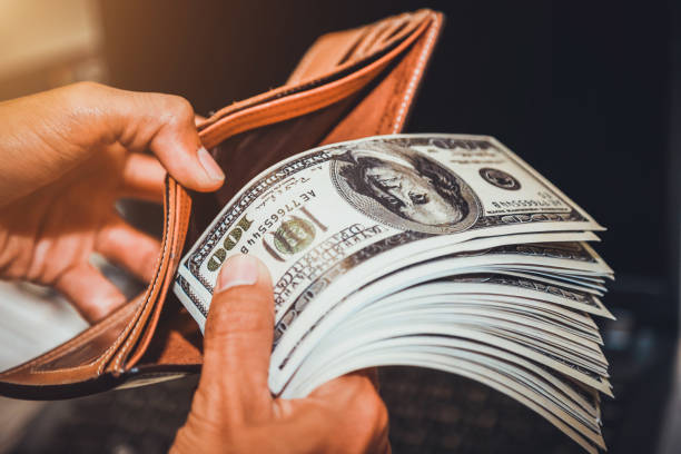 istock Hands holding us dollar bills and money pouch. 972498212