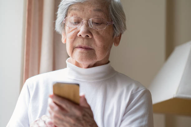 senior asian woman texting on smart phone - 96 well imagens e fotografias de stock